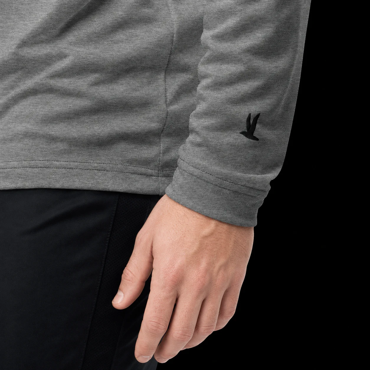 Close detail of the embroidered seabird at the sleeve of the heathered quarter-zip